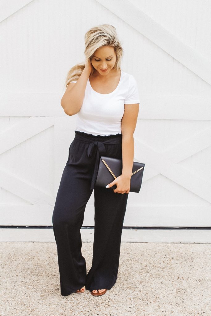 Frisco Fashion Blogger, Christina Solis is posing in a fitted plain white t-shirt tucked inside her black palazzo pants that have a high paper-bag waist. 